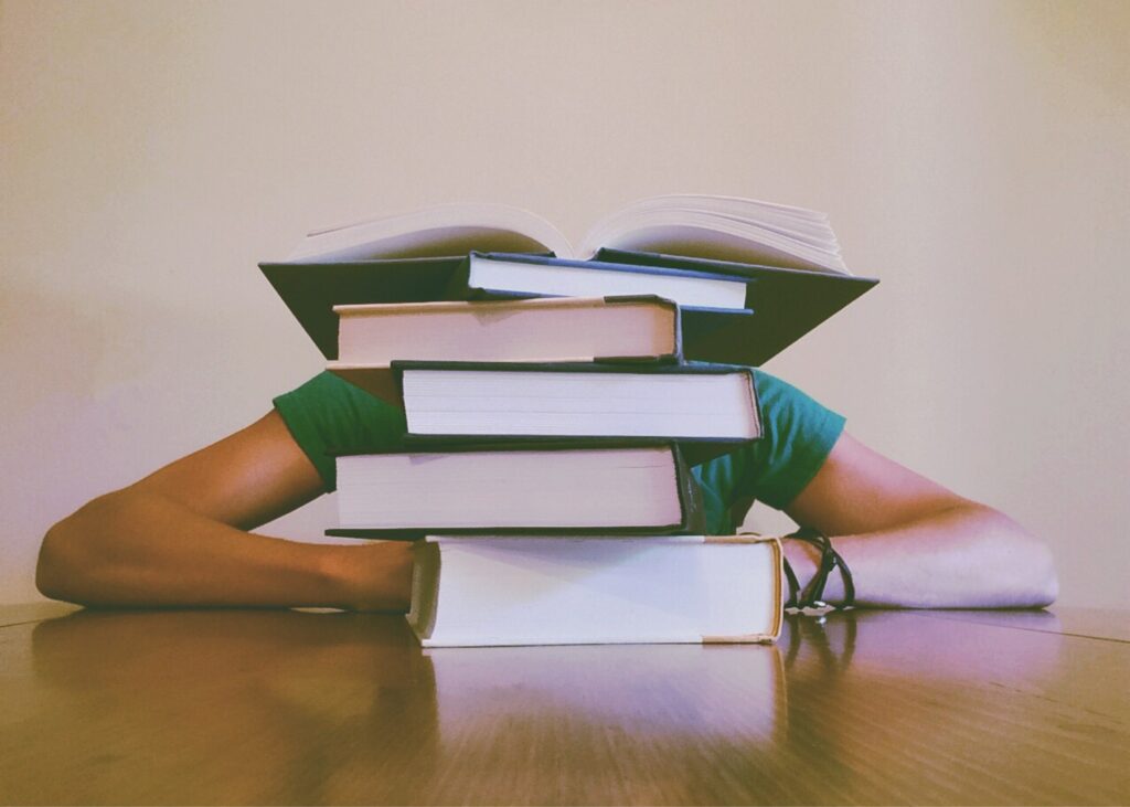 Stack of books in front of person sitting at table