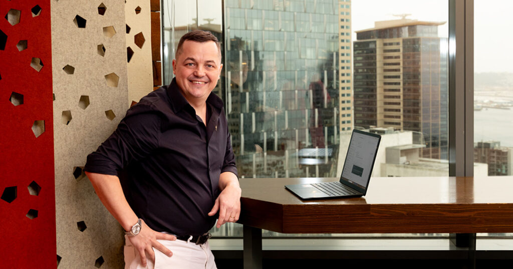 Student standing at a table with a laptop in their internship workplace