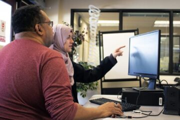 Staff member and student review tutoring services on a computer.
