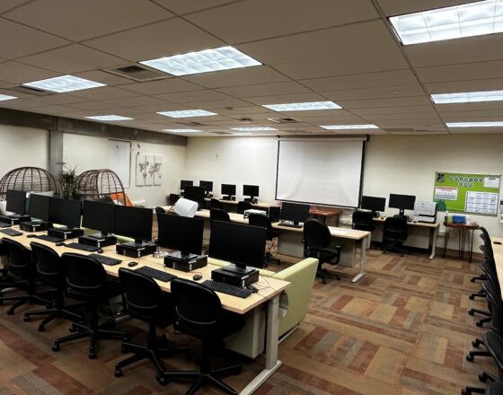 Classroom with a projector screen and rows of computers.