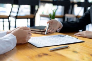 A focus on paper with two people sitting across the table from one another