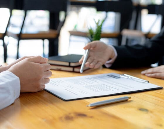 A focus on paper with two people sitting across the table from one another