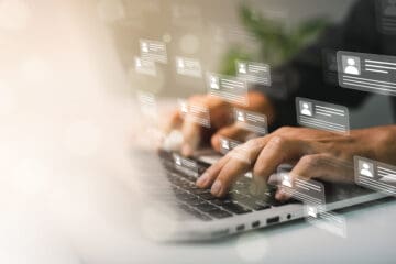 Someone typing on a laptop with 3D graphics around their hands