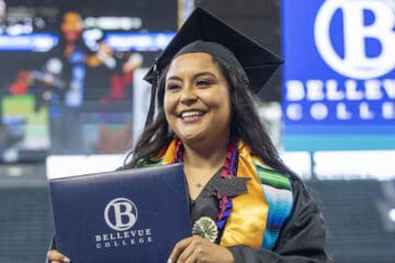 A recent Bellevue college student graduating and walking with their diploma