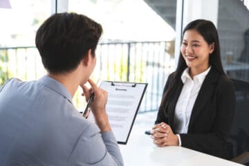 A women being interviewed by a person who is holding up their resume.