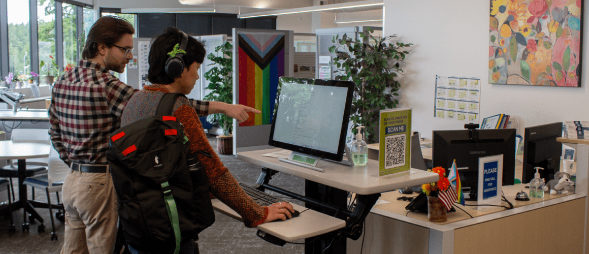 Career center employee showing a student how to check-in for their appointment at the Center for Career Connections in Bellevue College
