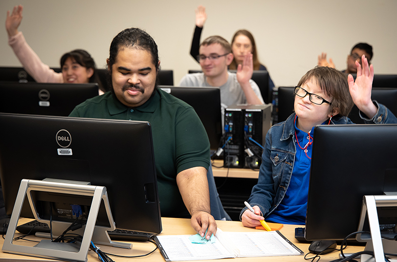 Occupational and Life Skills students raise their hands in class.