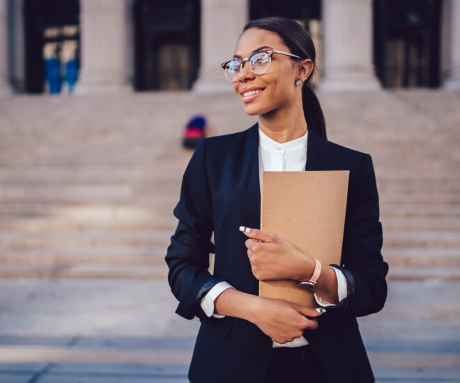 Woman standing in front of courthouse holding a folder.