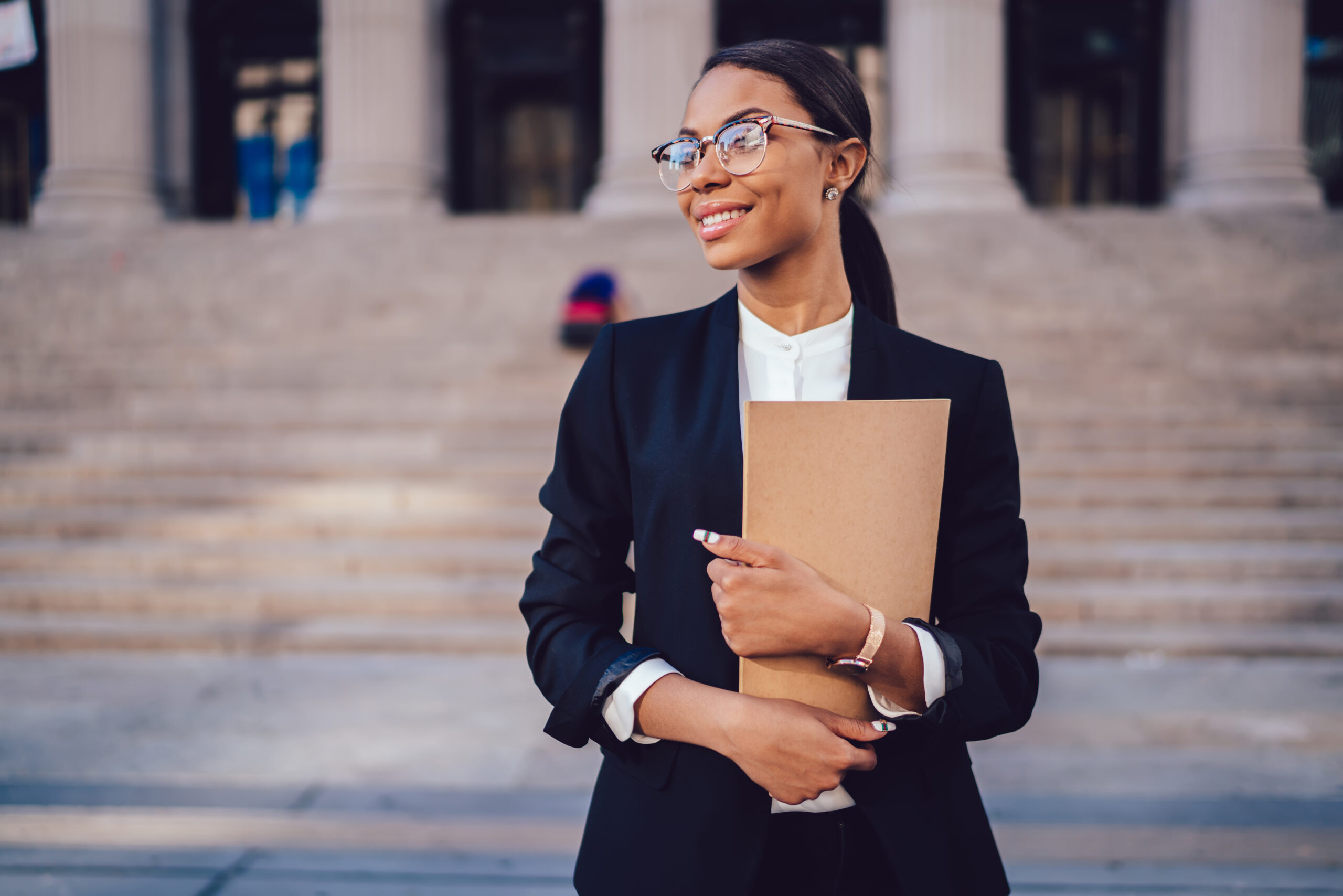 Woman standing in front of courthouse holding a folder.