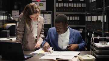 Two people talking at a desk in an evidence room
