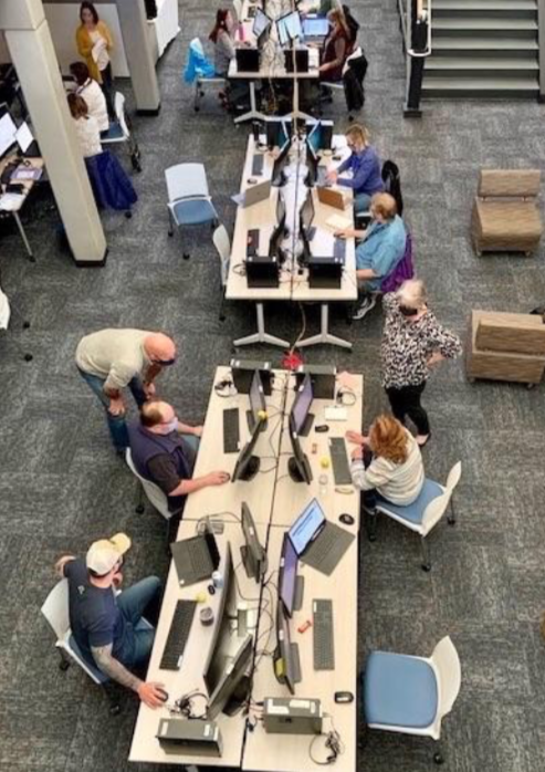 Employees busy at computer terminals on long tables