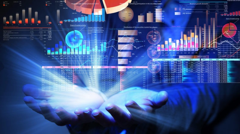 Hand with light and data graphs and charts superimposed
