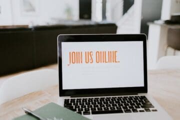 laptop sitting on table with 'Join us online' on the screen
