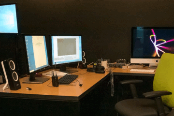 Studio Q setup with L-table, three monitors, external speakers and an office chair