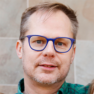 headshot of George Rowe wearing glasses and smiling