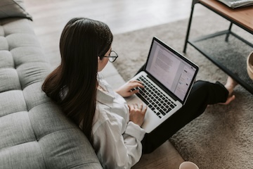 Female student sitting on the floor in her living room using a laptop