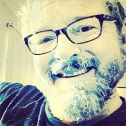 stylized headshot of Keith Rowley smiling, wearing glasses with a beard and mustache