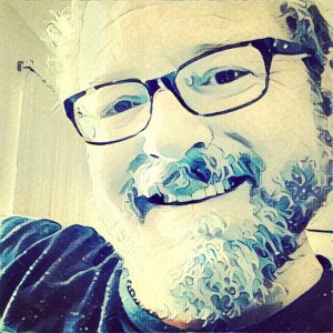 stylized headshot of Keith Rowley smiling, wearing glasses with a beard and mustache
