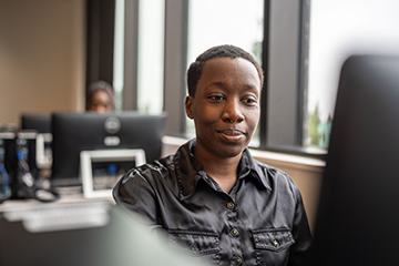 A student concentrates on their work in a computer lab.