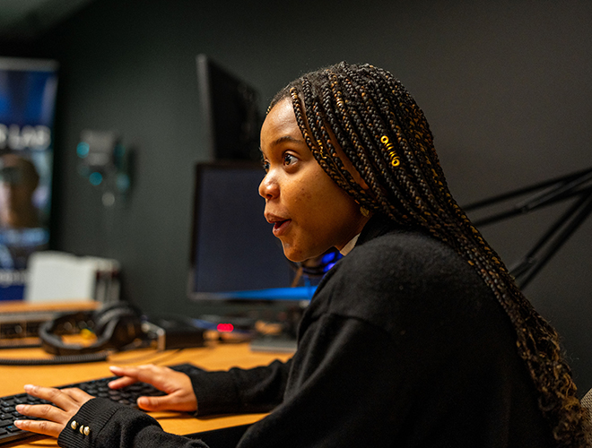A student makes an expression of joy and surprise while tapping on a keyboard.