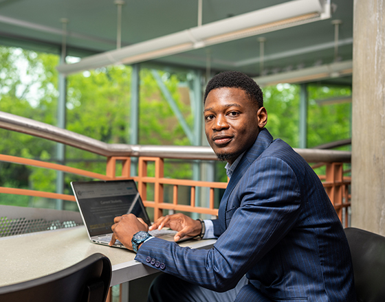 A student in a suit uses their laptop.