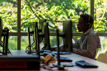 A student works on a desktop computer in a classroom setting.