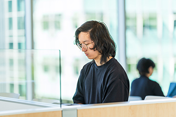 A student concentrates while working in a partitioned study space.