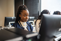 A student concentrates while working on a desktop computer.