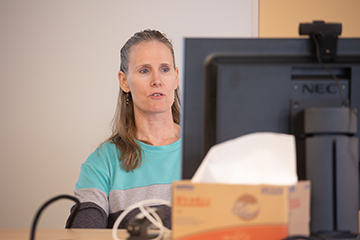 A faculty member works on a desktop computer.