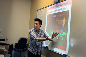A faculty member gestures while presenting a slide.