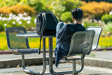 A student relaxes at an outdoor table on campus.