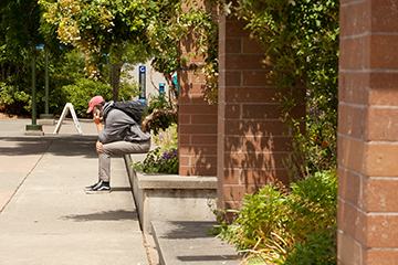 A student speaks on their phone while sitting outside.