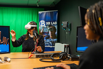 Students podcast from Studio Q while one wears a VR headset.
