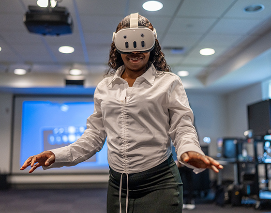 A student wearing a VR headset gestures in space.