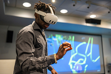 A student wears a VR headset in the XR Lab.