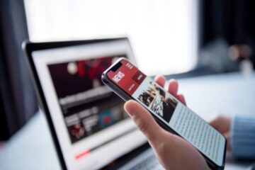 student on phone and laptop online