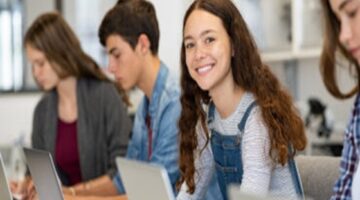 Students on the their laptops with a female smile toward the camera