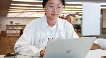 Students on the their laptops with a female smile toward the camera