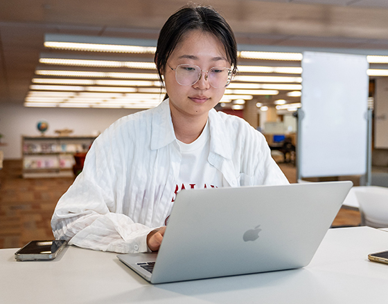 Students on the their laptops with a female smile toward the camera