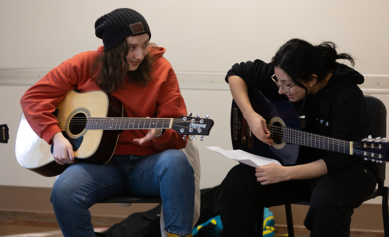 Students practice guitar together.