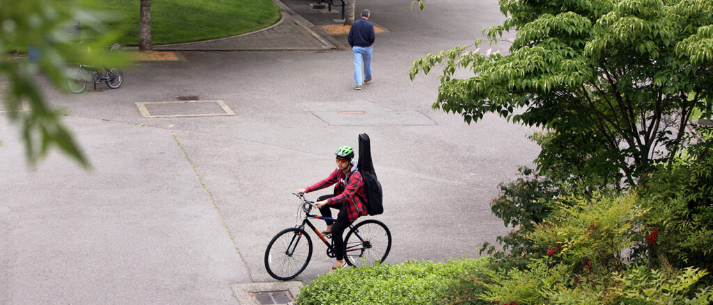 A student and their guitar bike through campus.