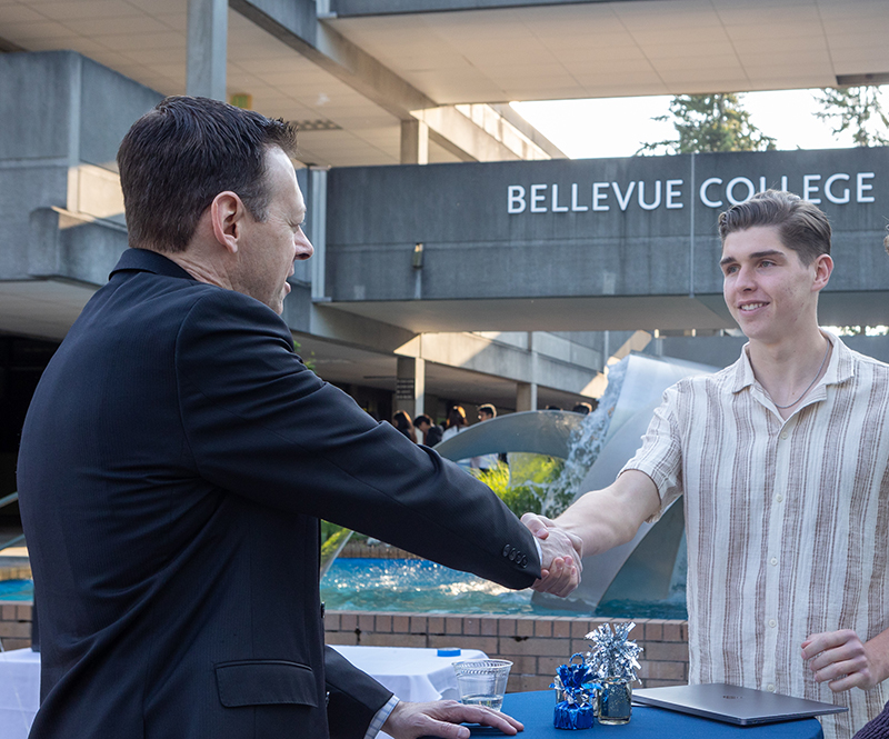 A local business leader meets a BC student at an outdoor gathering.