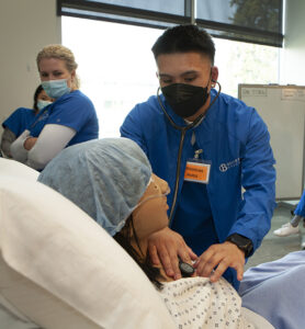 A student simulates a medical procedure in class.