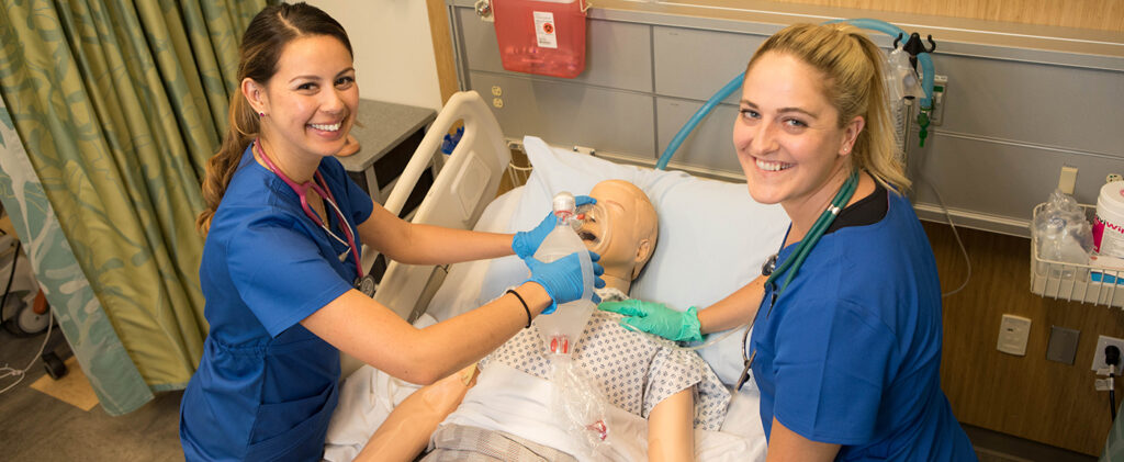 Students practice on a medical dummy during class.