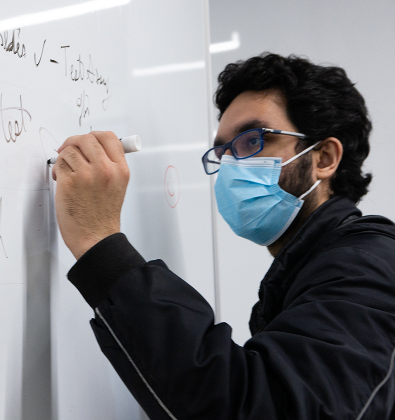 A student solves a problem on the whiteboard.