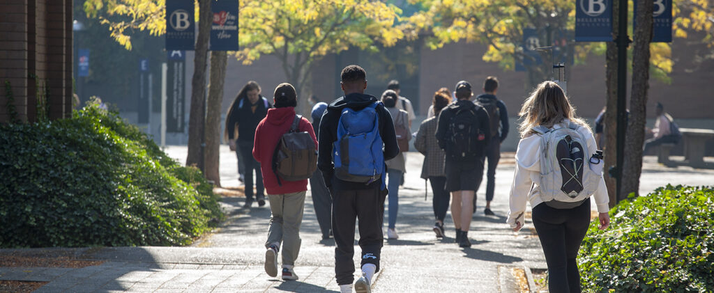 Students walk on BC campus in fall sunlight.