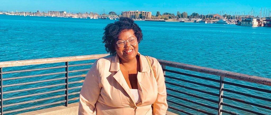 A BC student stands on a pier and smiles.