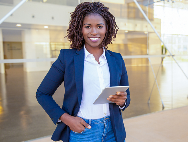 A businessperson poses outside of the office with a tablet.