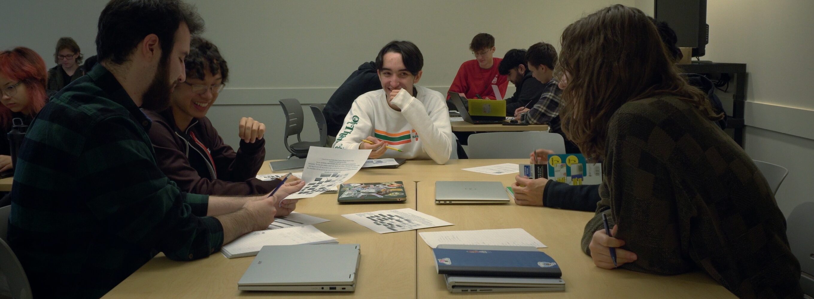 5 students sitting next to each other in a classroom and working with each other.