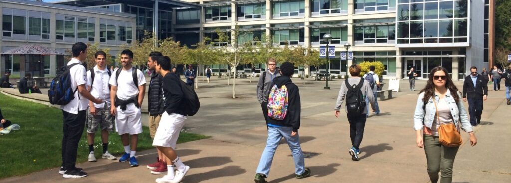 Students walking outside of Bellevue College through the courtyard on a sunny day